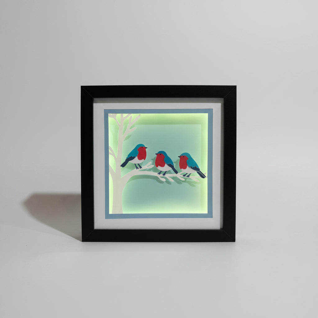 Framed artwork of birds on a branch with a blue background