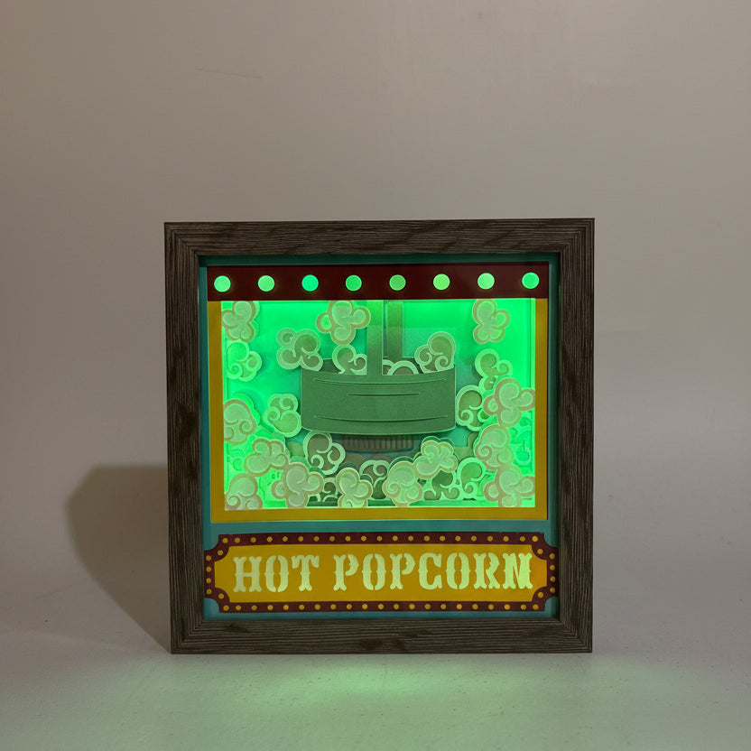 Decorative sign with 'Hot Popcorn' text and popcorn kernel design on a green background, framed in wood.