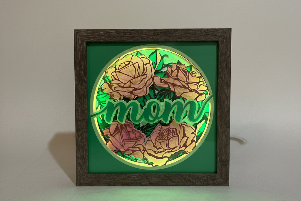 Decorative wall art with roses and 'mom' text in a wooden frame.