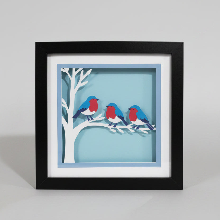 Framed artwork of birds on a branch against a blue background