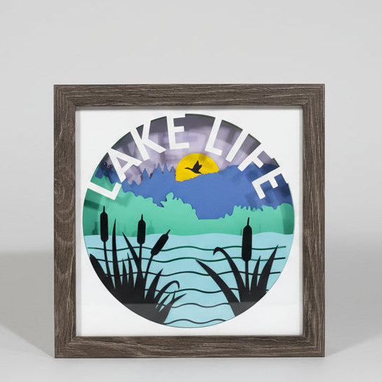 Framed artwork with 'Make Life Lake Life' text and nature-themed design on a beige wall.