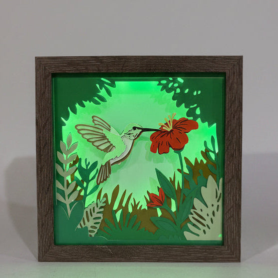 Decorative light box with a hummingbird and floral design on a green background, framed in wood.