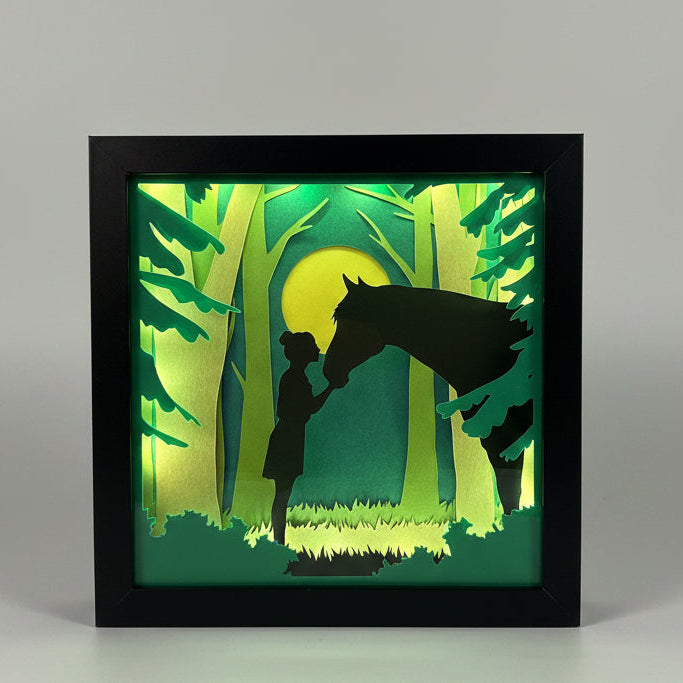 Framed artwork with silhouettes of people and horse against a green background